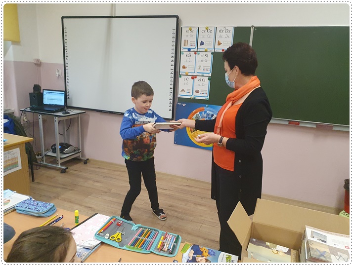 Pani bibliotekarka wręczająca uczniowi książki