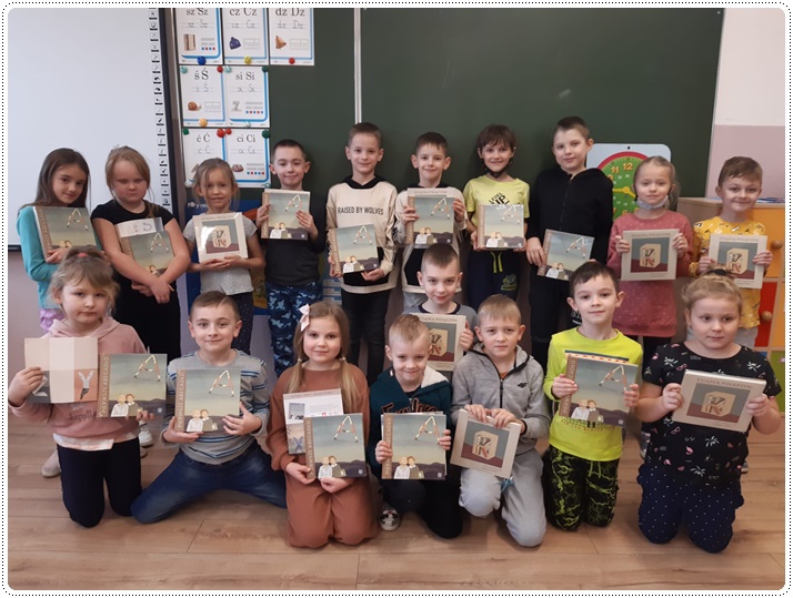 Uczniowie ustawieni w dwóch rzędach trzymający w rękach otrzymane książki
