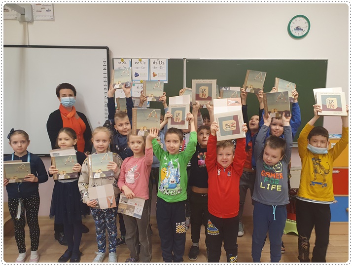 Uczniowie ustawieni w dwóch rzędach trzymający w rękach otrzymane książki