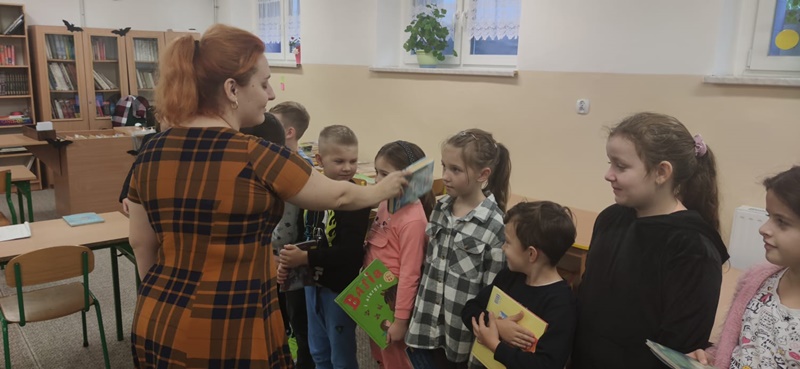 Pani bibliotekarka pasuje pierwszaków na czytelników biblioteki