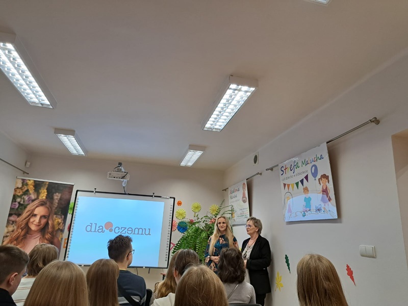 Na zdjęciu pisarka z dyrektorką biblioteki, w tle uczniowie