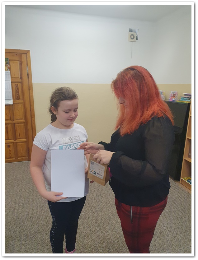 Bibliotekarka wręcza dziewczynce dyplom