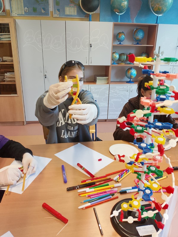 Uczennica trzymająca wykonany przez siebie model DNA z żelków