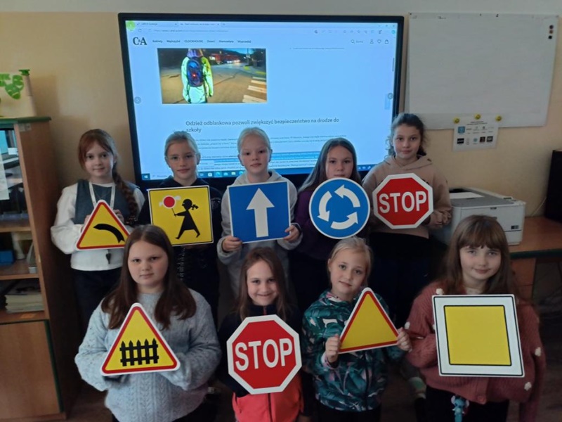 Uczniowie stojący w grupie, trzymają znaki drogowe Uczniowie stojący w grupie, trzymają znaki drogowe